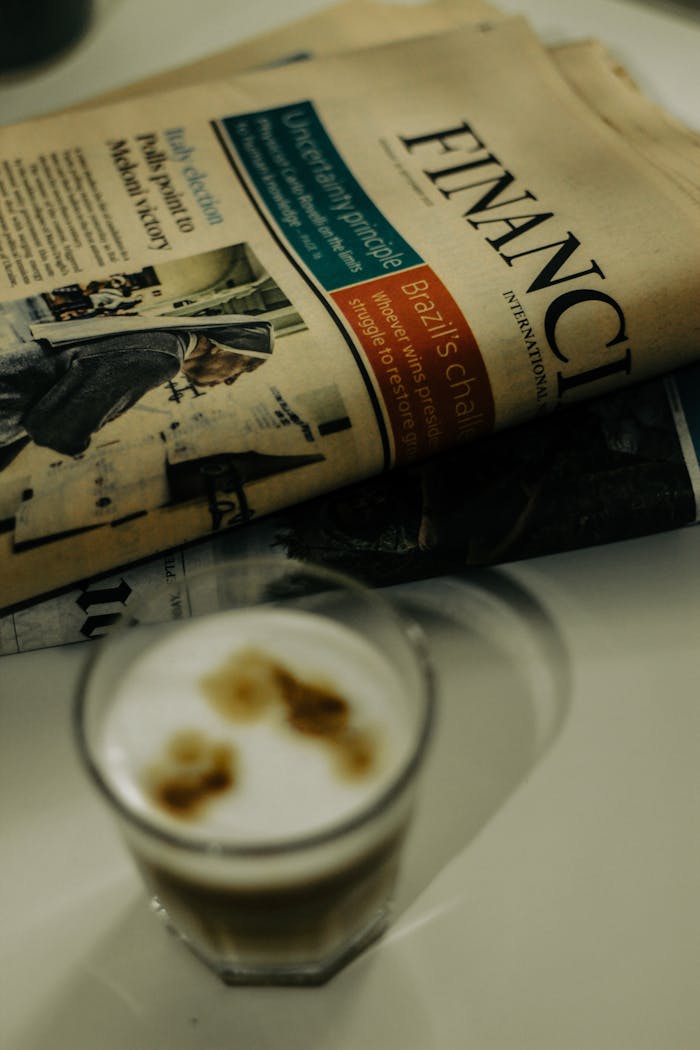 Home Close-up of a financial newspaper and coffee cup on a desk, ideal for finance themes.