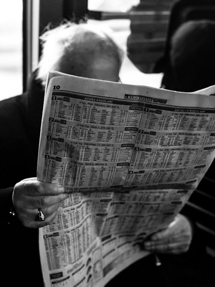 About Black and white photo of an elderly man reading a newspaper in İstanbul.